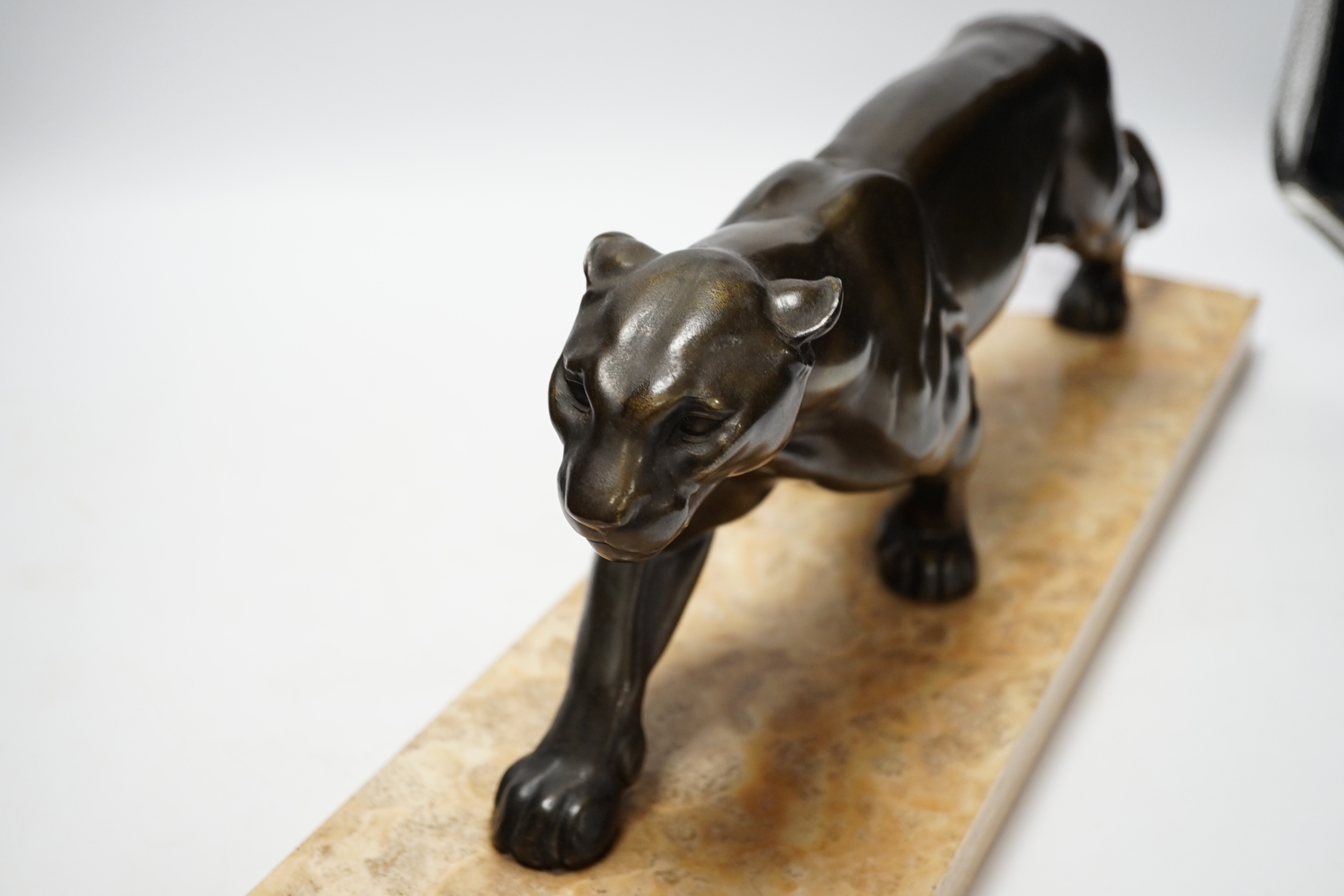 A French Art Deco bronzed metal model of a panther on a marble base, base 55cm wide